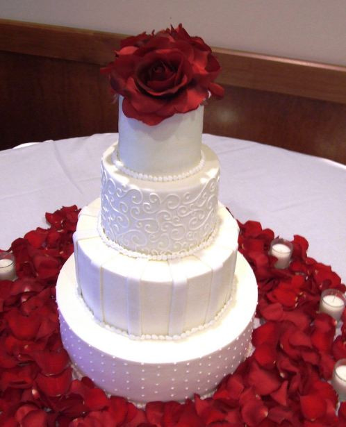 White Wedding Cake With Red Roses
 Four tier white wedding cake with red rose on top with